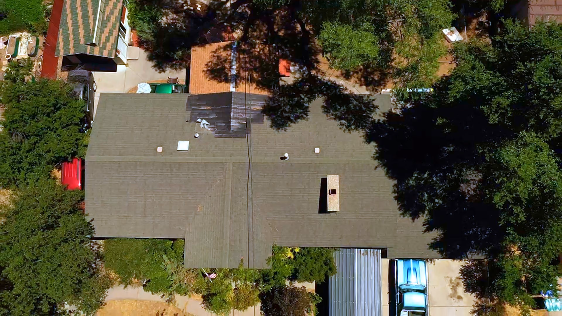 Aerial view of an Orem, Utah home before roof replacement, showing a worn asphalt shingle roof with a tarped section near the chimney