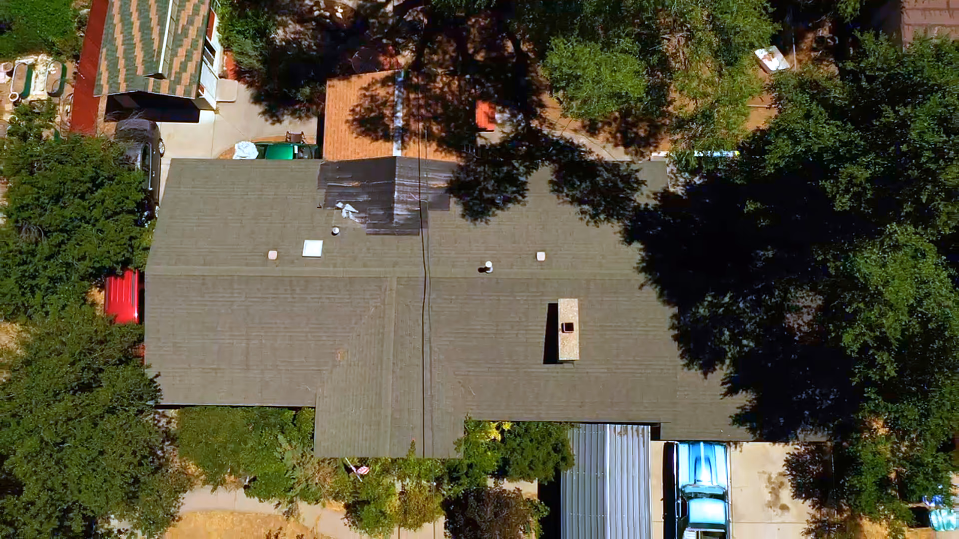 Aerial view of an Orem, Utah home before roof replacement, showing a worn asphalt shingle roof with a tarped section near the chimney